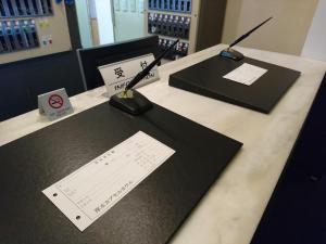 a desk with black mats and a paper on it at Atsugi Capsule Hotel in Atsugi