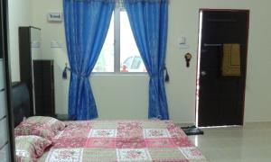 a bedroom with a bed and a window with blue curtains at Homestay Kg Paya D Jitra in Jitra
