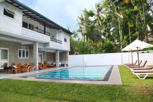 a house with a swimming pool next to a yard at Hikka Nature Villa in Hikkaduwa