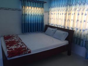 a bedroom with a bed with blue curtains at HOTEL Thành Nam in Long Hai