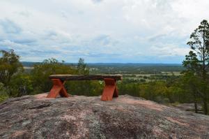 a wooden bench sitting on top of a rocky hillside at 31 The Rocks in Stanthorpe