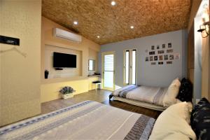 a bedroom with two beds and a flat screen tv at Macaron B&B in Luodong