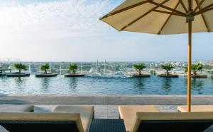 una piscina de agua con sillas y sombrilla en The Tower Plaza Hotel Dubai, en Dubái