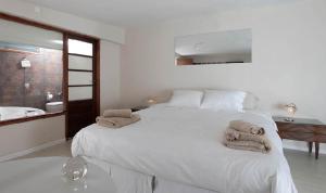 a white bedroom with a large bed with towels on it at Casabierta in Buenos Aires