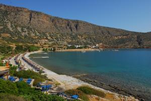a beach with a bunch of chairs and the water at Athina Villas in Elounda