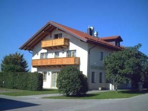 Casa blanca con balcón en la parte superior. en Pension Demmel, en Bruckmühl