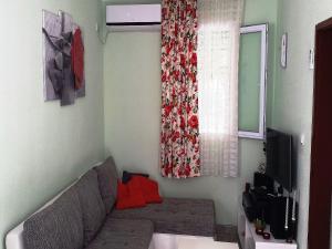 een woonkamer met een bank en een raam bij Holiday Home Aksentijevic in Sutomore