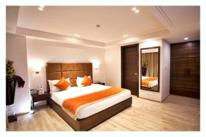um quarto com uma cama grande e almofadas laranja em Kaisons Inn (Near Apollo Hospital) em Nova Deli