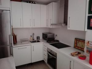 a small kitchen with white cabinets and a microwave at Precioso Piso junto a Plaza de España in Seville +9 photos