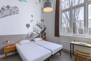zwei Betten in einem Zimmer mit zwei Fenstern in der Unterkunft Stayokay Hostel Amsterdam Oost in Amsterdam