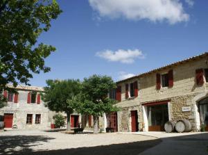a stone building with red shuttered windows and a tree at Mas du Notaire in Gallician