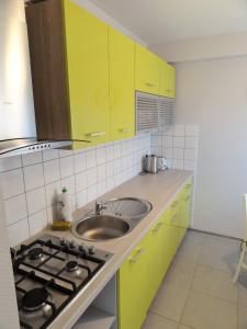 een keuken met gele kasten en een wastafel bij Apartament CamInSki in Kudowa-Zdrój