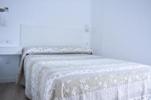 Un dormitorio con una cama con una manta blanca. en Apartamentos San Agustín en Murcia