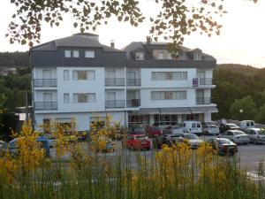 a large white building with cars parked in a parking lot at Hotel Conde in Taboadela
