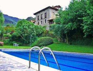 a swimming pool with a building in the background at Albergue Turístico Valdebaró in Camaleño