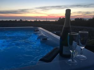 トッレ・スーダにあるFranco's Trullo with Sea Viewのホットタブのそばでボトルワイン1本とワイングラス2杯