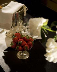 a bowl of strawberries on a table with wine glasses at YH Jacuzzi Suite in Rome