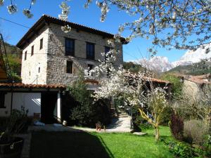 an old stone house with mountains in the background at Albergue Turístico Valdebaró in Camaleño