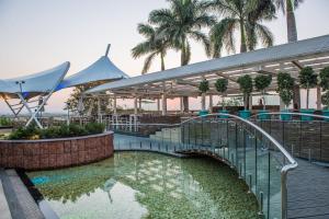 a swimming pool with a bridge and palm trees at The Red Maple Mashal in Indore