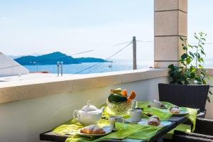 a table with food on a balcony with a view of the ocean at Apartment Bonaca in Dubrovnik