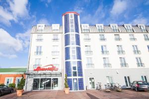 a tall white building with a red sign on it at Select Hotel Elmshorn in Elmshorn