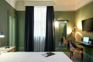 a hotel room with a bed and a desk and a window at Mercure Bristol Grand Hotel in Bristol