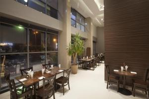 a restaurant with wooden tables and chairs and windows at Watheer Hotel Suite in Dammam