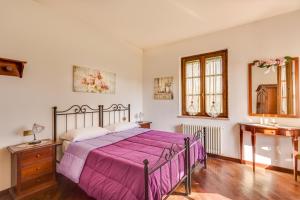 a bedroom with a large bed with a purple blanket at Country House Podere Le Rane Felici in Fauglia