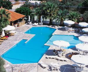 an overhead view of a swimming pool with white umbrellas at Klonos Anna in Egina