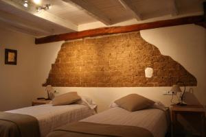 two beds in a room with a brick wall at La Nogala in Dobro