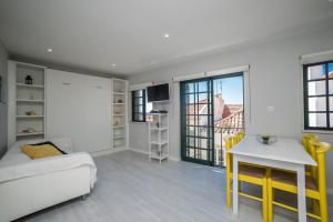 a living room with a bed and a table with yellow chairs at Apartamento Casa Amarela in Sesimbra