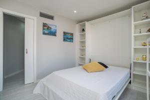 a white bedroom with a bed and shelves at Apartamento Casa Amarela in Sesimbra