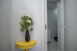 a yellow table and a vase with flowers on it at Apartamento Casa Amarela in Sesimbra +9 photos