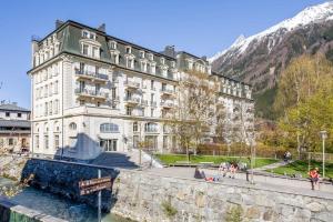 un gran edificio blanco con montañas en el fondo en Mont Blanc 98 Apartment - Chamonix All Year, en Chamonix-Mont-Blanc