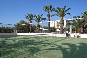 a tennis court with palm trees in front of a building at Klonos Anna in Egina