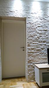 Cette chambre est dotée d'un mur en briques blanches et d'une porte. dans l'établissement Apartment Alsa, à Mostar