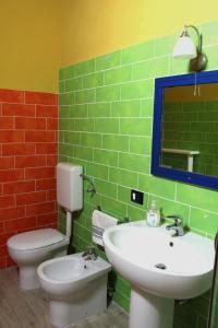 a bathroom with a sink and a toilet and a mirror at CasaTua Punta Secca in Punta Secca