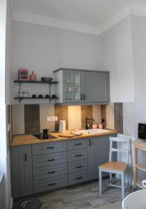a kitchen with grey cabinets and a white chair at Óváros Apartman in Veszprém