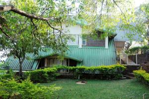 ein grünes Haus mit einem Baum im Hof in der Unterkunft Wind Chalet in Koynanagar