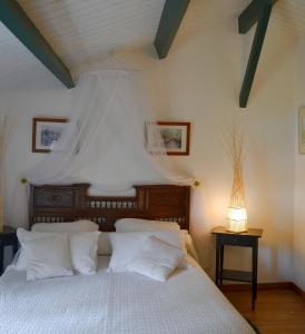 een slaapkamer met een bed met witte kussens bij Le Petit Massigny in Velluire