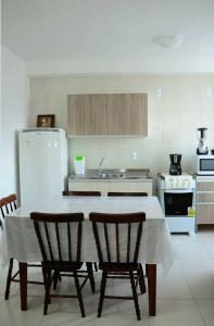 cocina con mesa, sillas y nevera en Apartamento linda vista para o mar Penha Parque Beto Carrero, en Penha