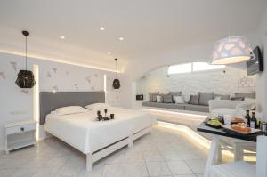 a white bedroom with a bed and a living room at Naxos Evilion Luxury Apartments & Suites in Naxos Chora