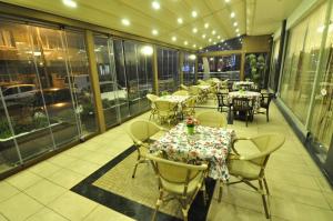 ein Restaurant mit Tischen, Stühlen und Fenstern in der Unterkunft Elit Asya Hotel in Balıkesir