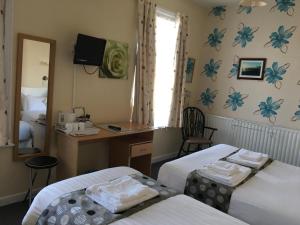 a room with two beds and a desk and a mirror at The Address in Blackpool