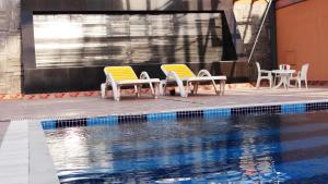 two chairs and a table and a swimming pool at Crystal Palace Hotel in Manama