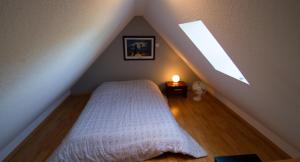 ein Schlafzimmer mit einem weißen Bett im Dachgeschoss in der Unterkunft Les gites de Georgia in Voegtlinshoffen