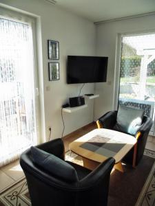 ein Wohnzimmer mit Stühlen, einem Tisch und einem TV in der Unterkunft Ferienwohnung Am Schlosspark in Putbus