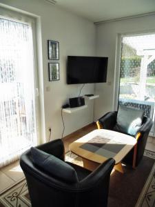 een woonkamer met stoelen en een tafel en een televisie bij Ferienwohnung Am Schlosspark in Putbus