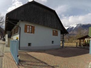 a white house with a black roof and mountains in the background at Lesjakova Domačija in Bovec