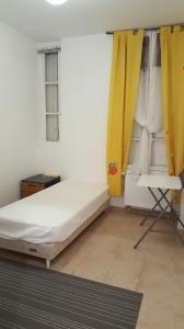 - une chambre avec un lit et un rideau jaune dans l'établissement Chambres à PARIS, à Ivry-sur-Seine